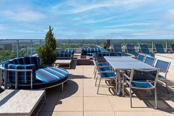 A patio with blue and white striped chairs and tables at Two Twelve Clayton Apartments, Missouri, 63105